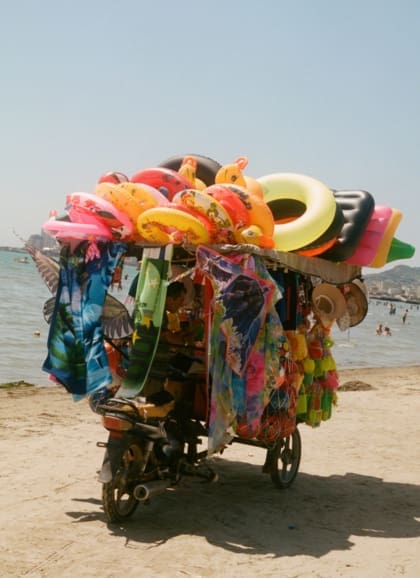 Hazel Gaskin photographs Albania | a cart on a beach in Durres groans with colourful merchandise, like inflatable rings in a rainbow of colours