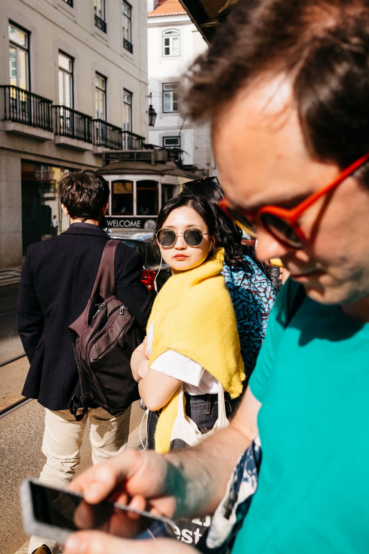 A woman wearing sunglasses and a yellow jumper in Lisbon, candidly captured by photographer Emma Croman