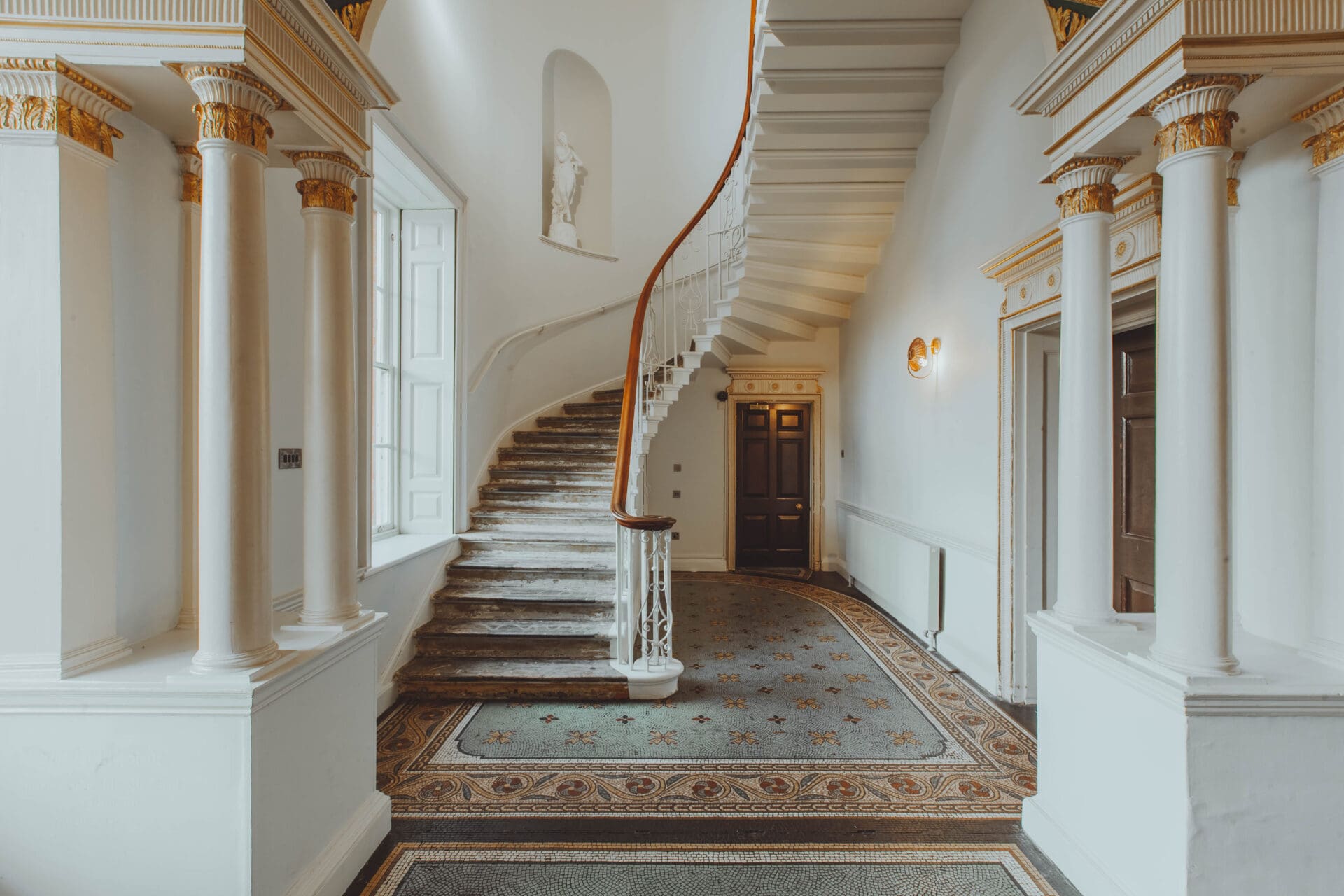 Where to co-work in London | an ornate curved staircase in a hall with classic-style columns and a tiled floor at Birch Community