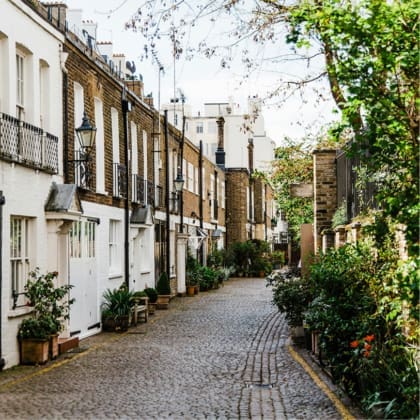 A cobblestone street lined with lamp posts and greenery in London