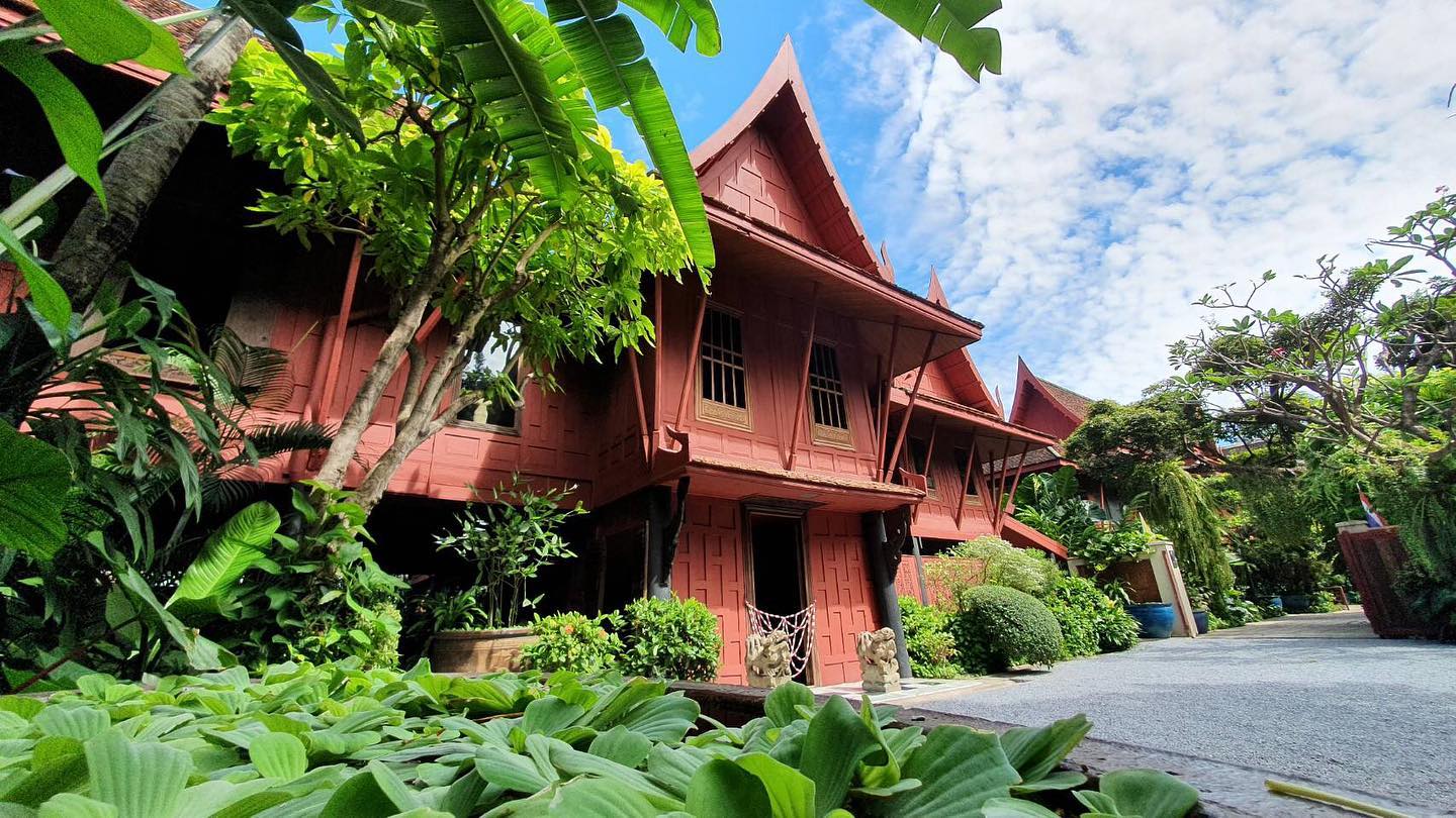 The best museums and galleries in Bangkok | a view of the teak wood exterior of Jim Thompson House Museum, with vivid green trees and plants in the foreground