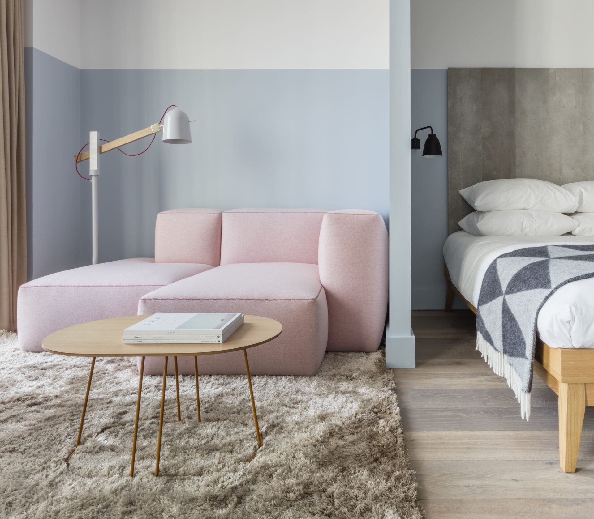 Where to stay in London | A pale-pink sofa and a coffee table on a fluffy rug in a pale-blue room and the edge of a made bed at Leman Locke Apartments