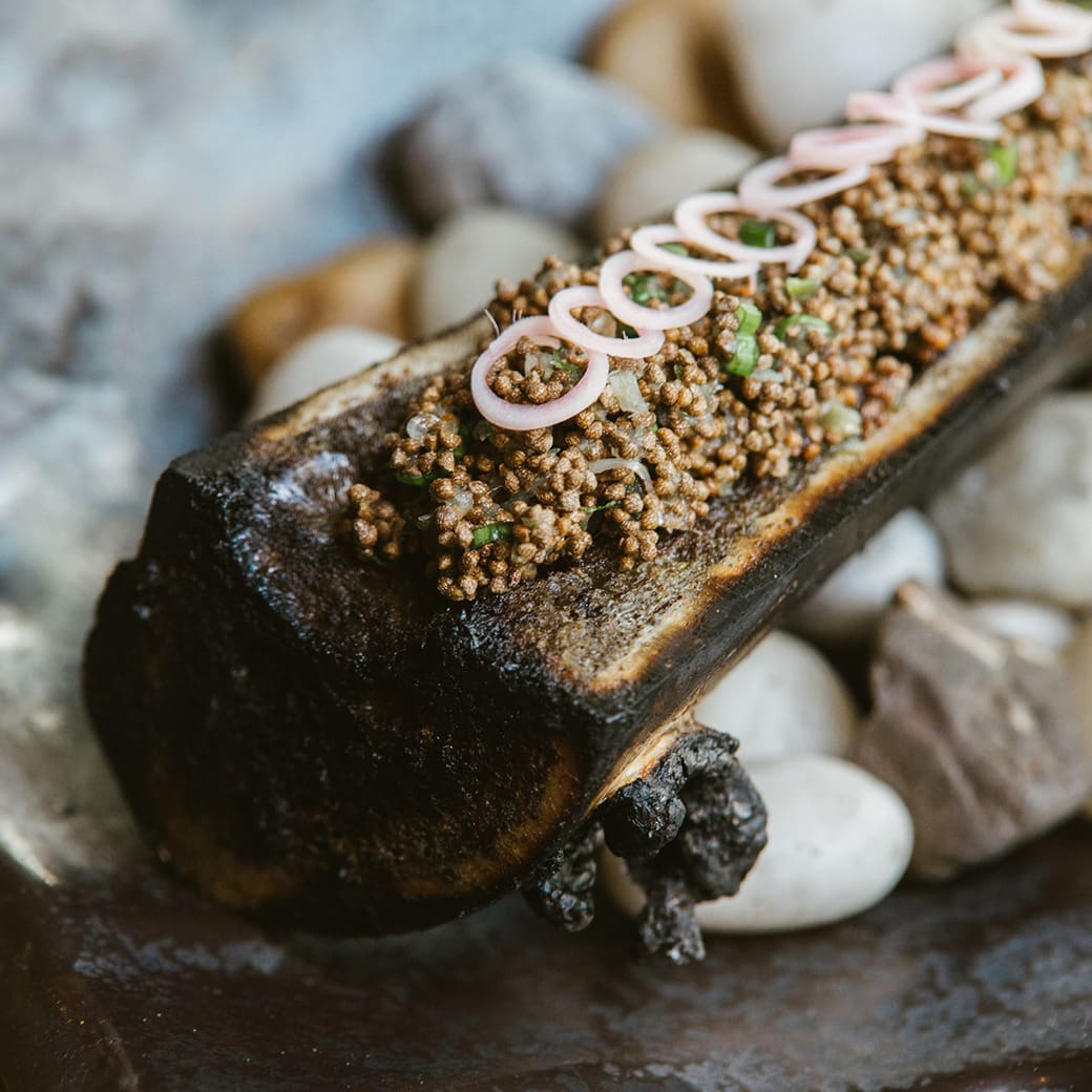 Bangkok's best restaurants: roasted bone marrow topped with delicate onion rings, served prettily atop some pebbles at Mahaseth