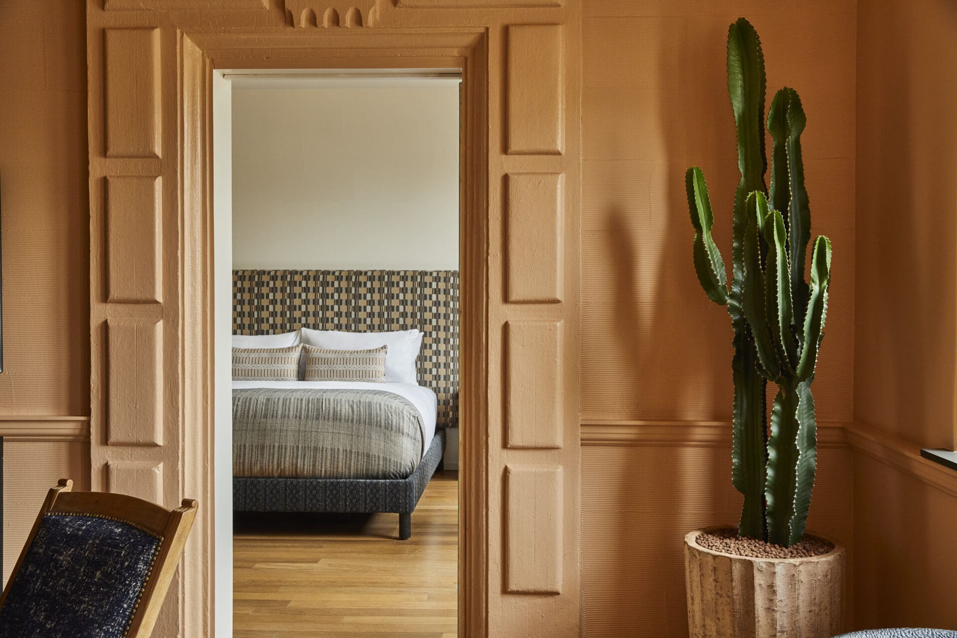 Places to stay in LA | A bedroom in Downtown LA Proper Hotel, with terracotta-toned walls and a potted cactus beside the door.