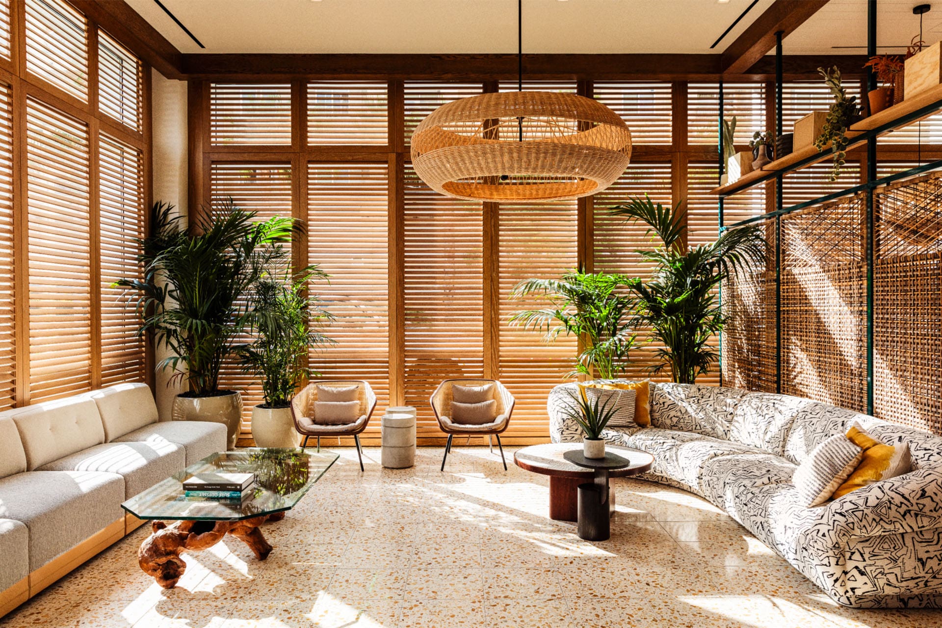 The best places to stay in LA | An interior view at The Hotel June. Wooden blinds cover the windows, a rattan light shade hangs from the centre of the ceiling, and two sofas flank the lounge on either side