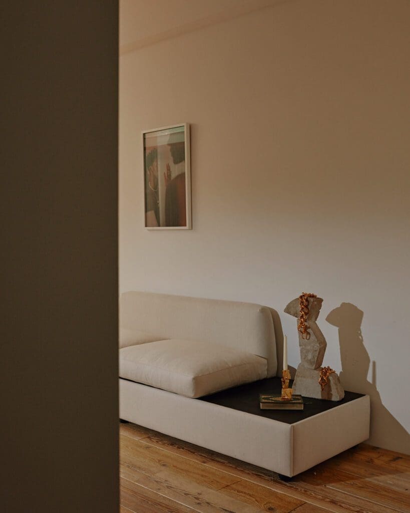 Rosh Mahtani of Alighieri | A white sofa in front of a white wall, with a side table topped with jewellery and objects
