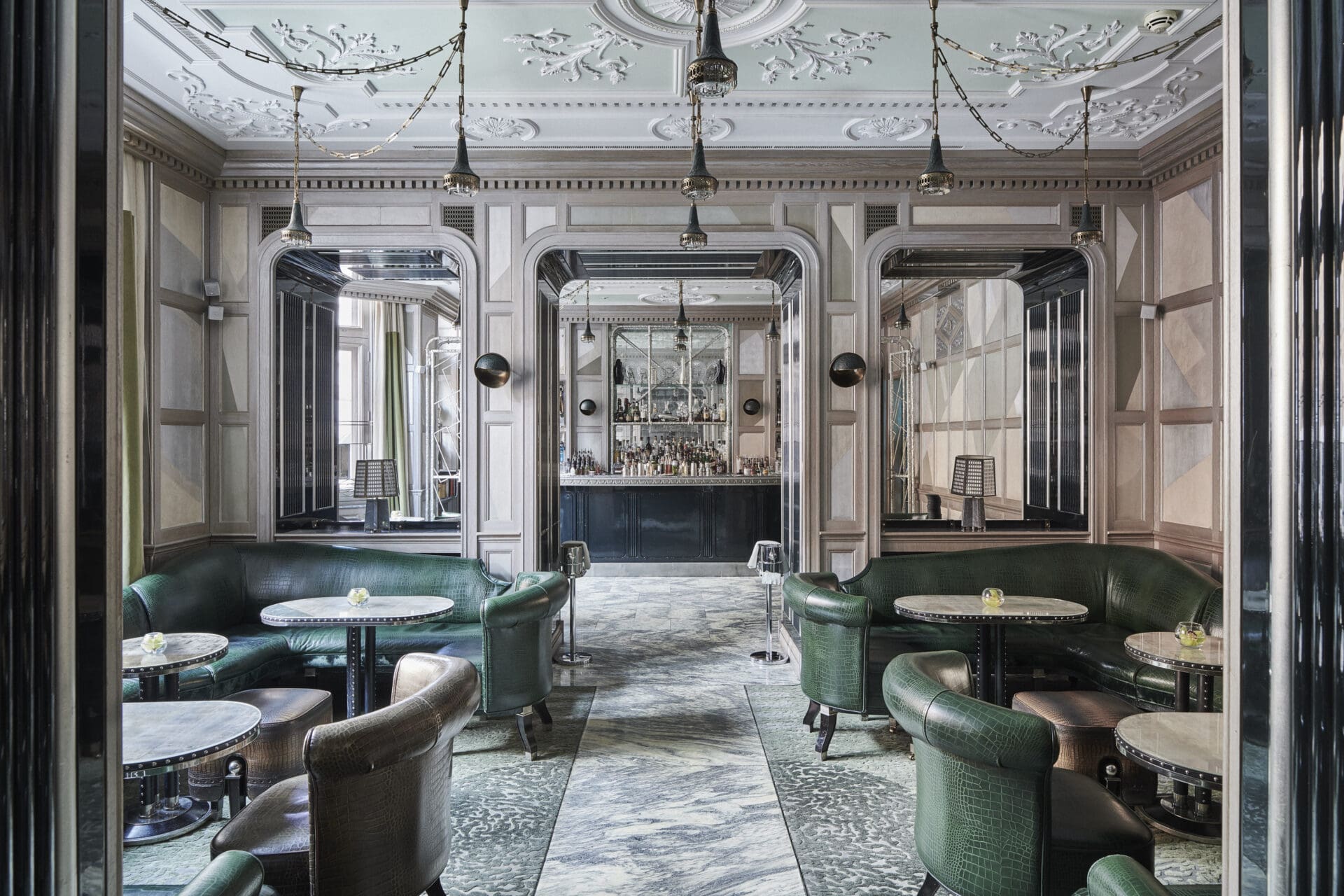 London's best cocktail bars | Green leather sofas and chairs inside a pale-pink room with marble flooring at iconic hotel bar The Connaught
