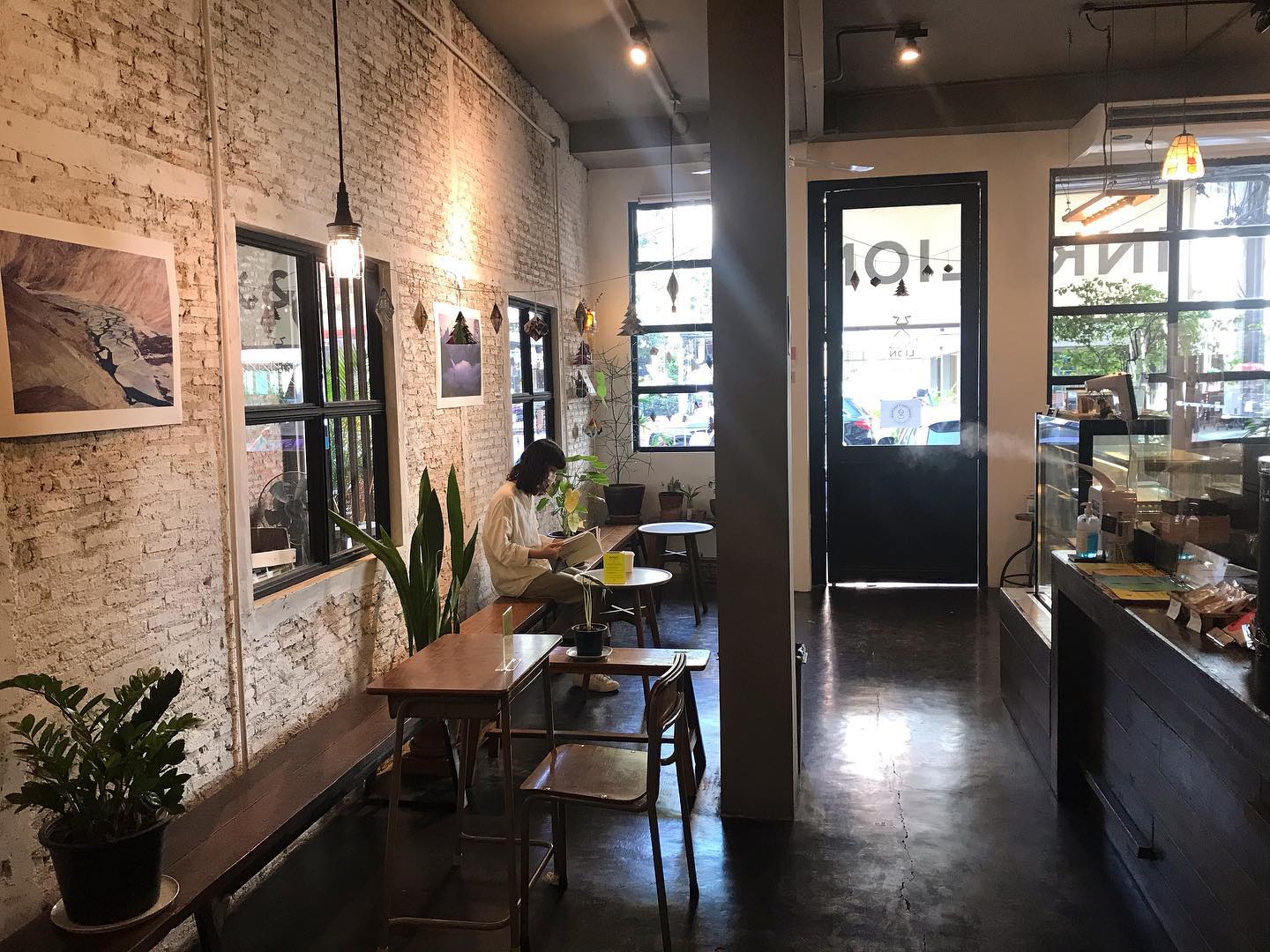 Where to co-work in Bangkok | concrete floors, whitewashed open brick walls and low seating surrounded by green plants at Ink & Lion
