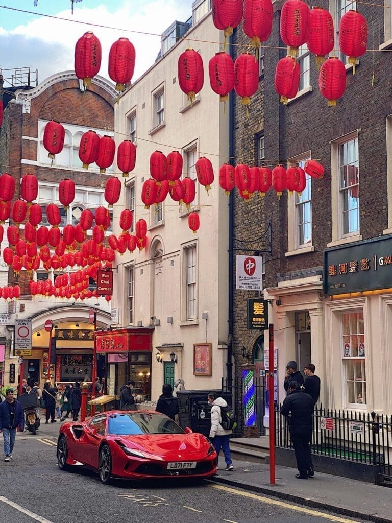 Local's guide to London | Strings of red lanterns hanging across the streets in London's Chinatown, with a bright-red Ferrari sportscar underneath