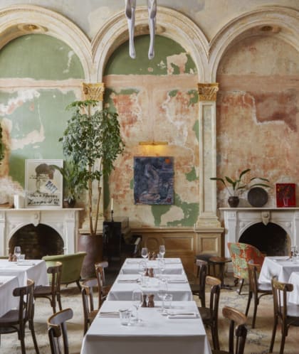 Best restaurants in London | Tables lie in wait with cutlery and pristine white tablecloths in the dining room at Sessions Arts Club, in front of bare stripped walls and twin fireplaces