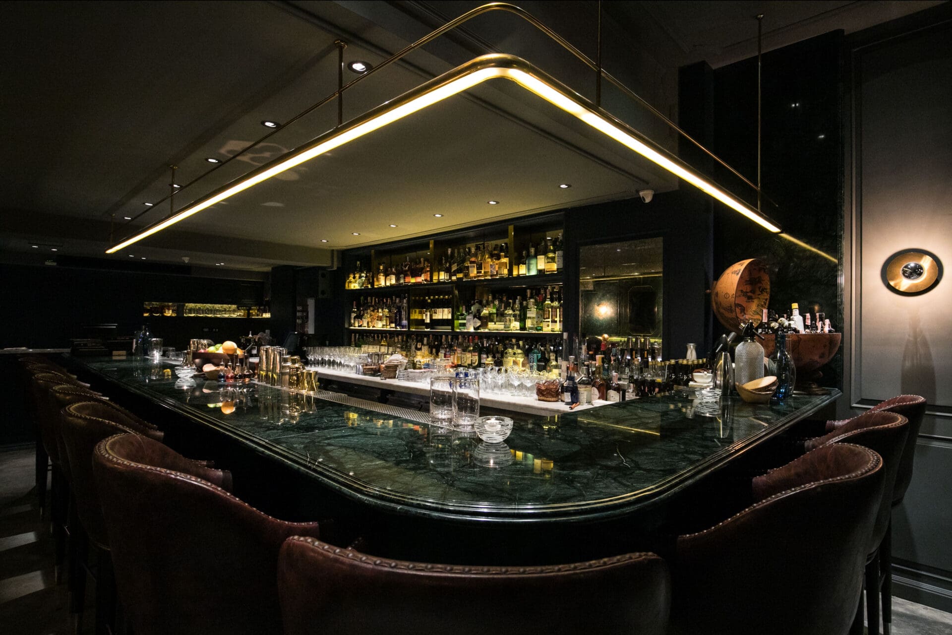 Best bars in Bangkok | A green marble-topped bar and dark brown leather stools at Vesper