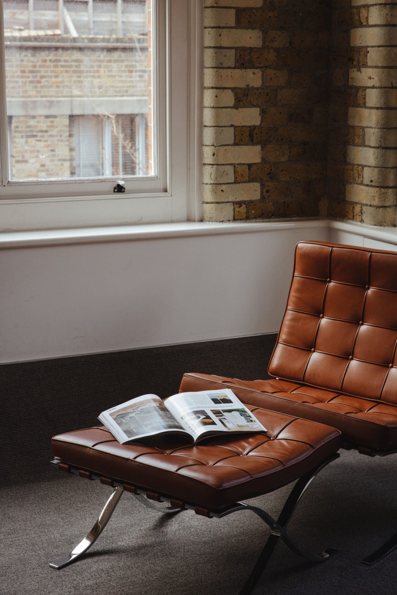 Best hotels in Shoreditch, Dalston and Hackney | A brown leather Barcelona chair and foot rest in a corner of a room inside Boundary, with a magazine opened on the foot rest.