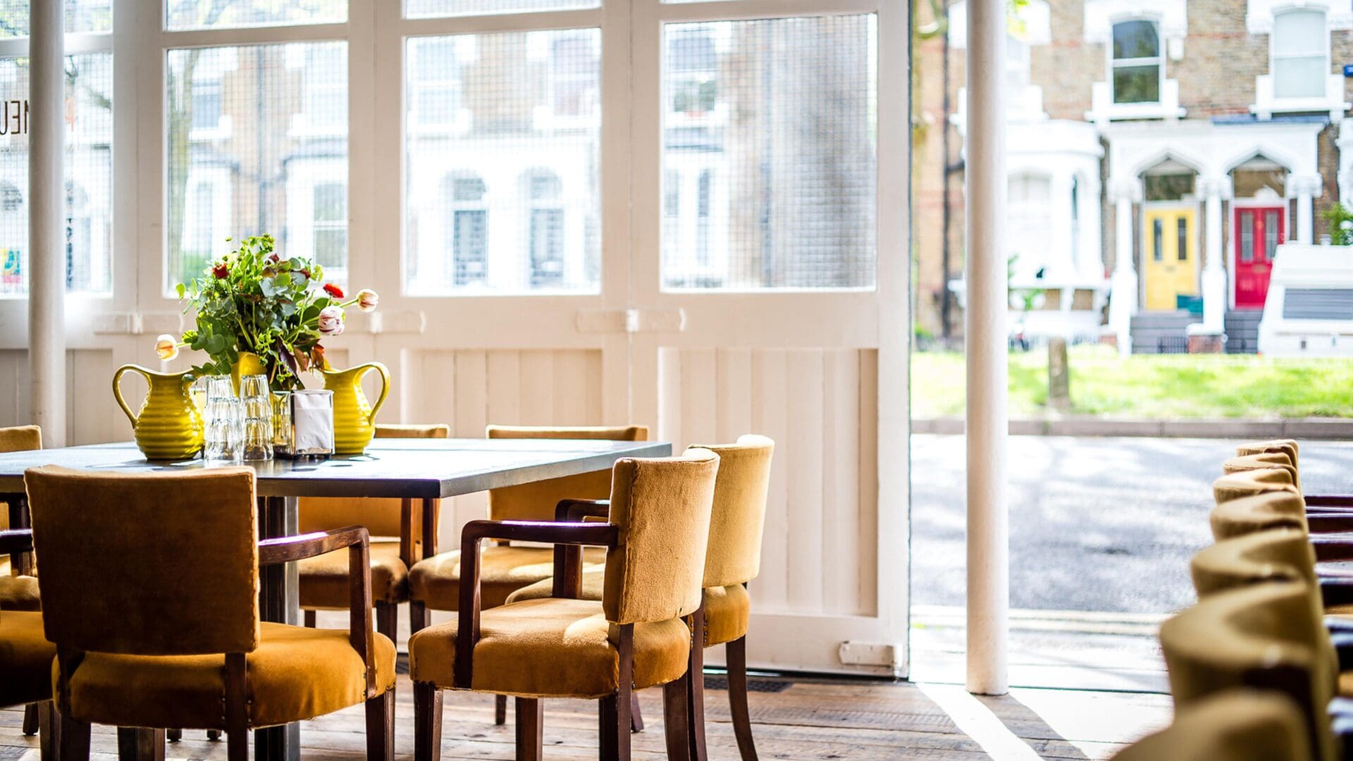 The best restaurants in Hackney | an interior view of Primeur, with a table and armchairs in view, and an arrangement of flowers and small yellow ceramic jugs on the table