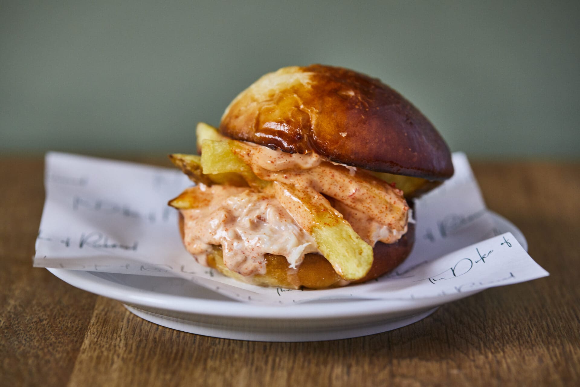 The best restaurants in Hackney | The crab chip butty on some paper, on a plate, on a wooden table, inside The Duke of Richmond pub