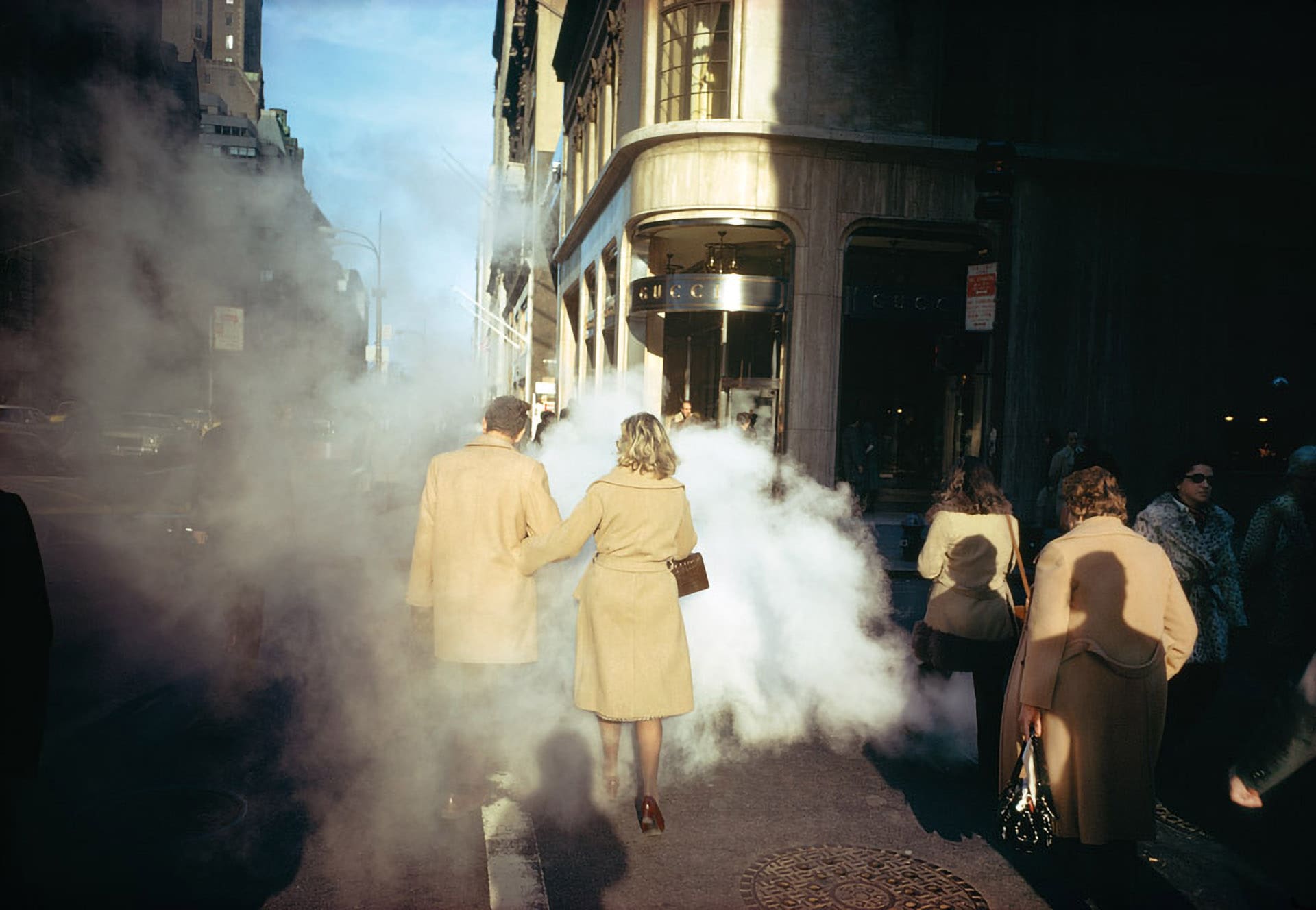 A couple walk through steam in a New York City street. Photographed by Joel Meyerowitz