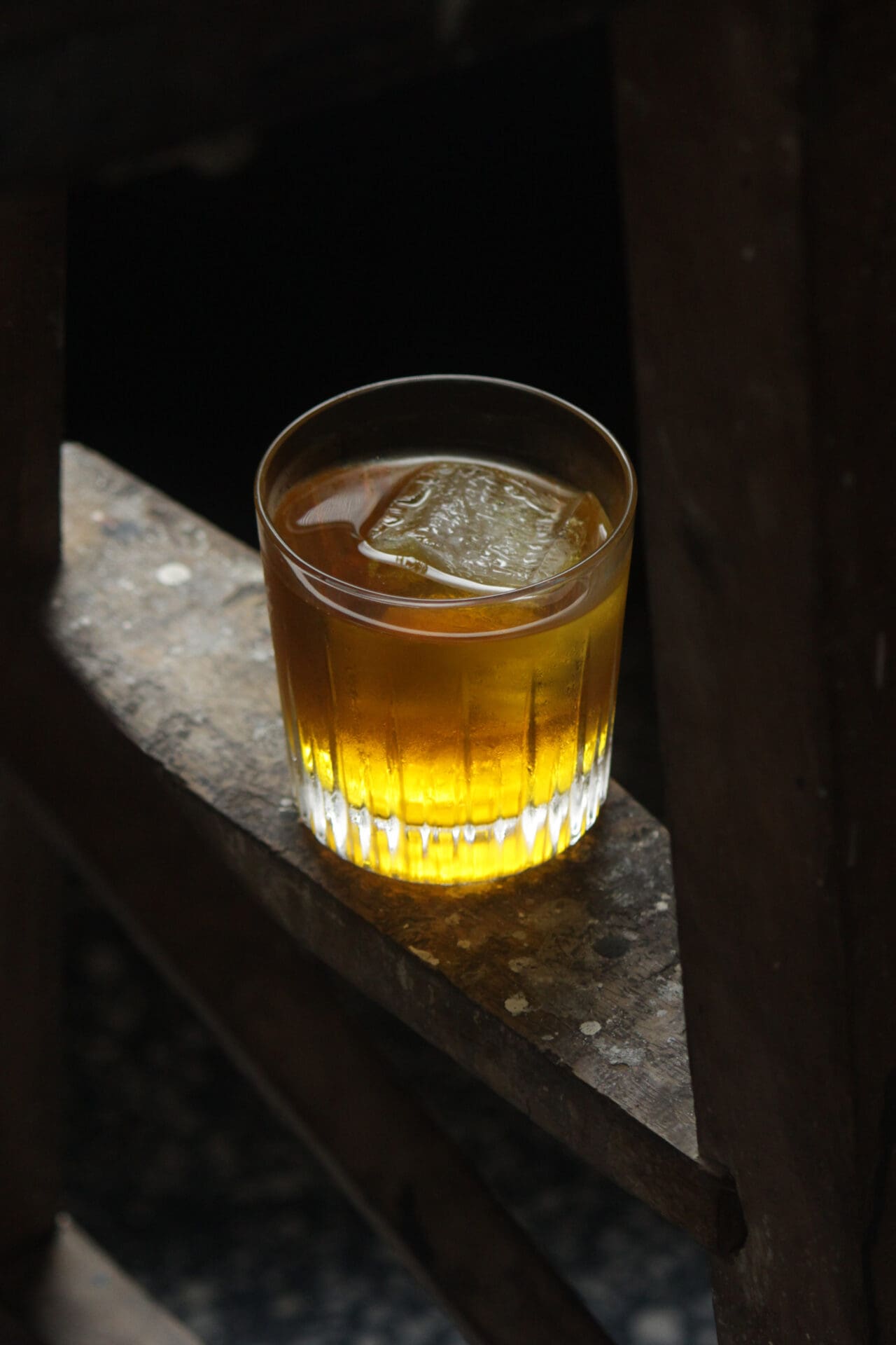 Best bars in Mumbai | A white negroni, served on a dark stone tabletop, with a large ice cube in the drink