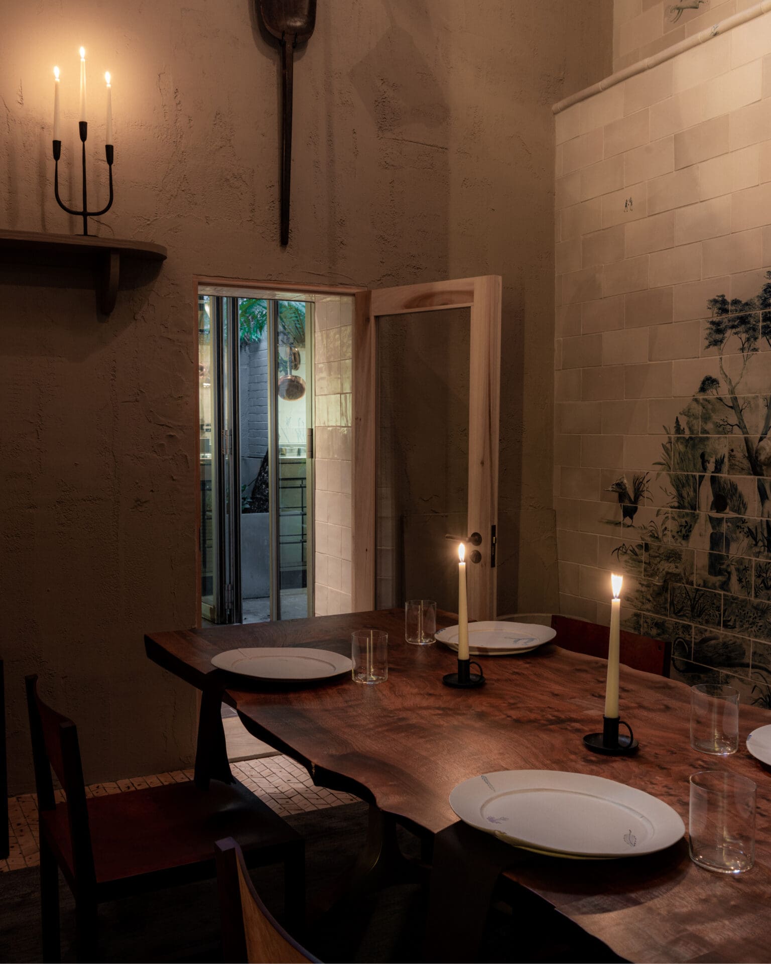The best private dining rooms in London | A candlelit dining room with a long wooden table laid out with plates and glasses at Cycene, Shoreditch