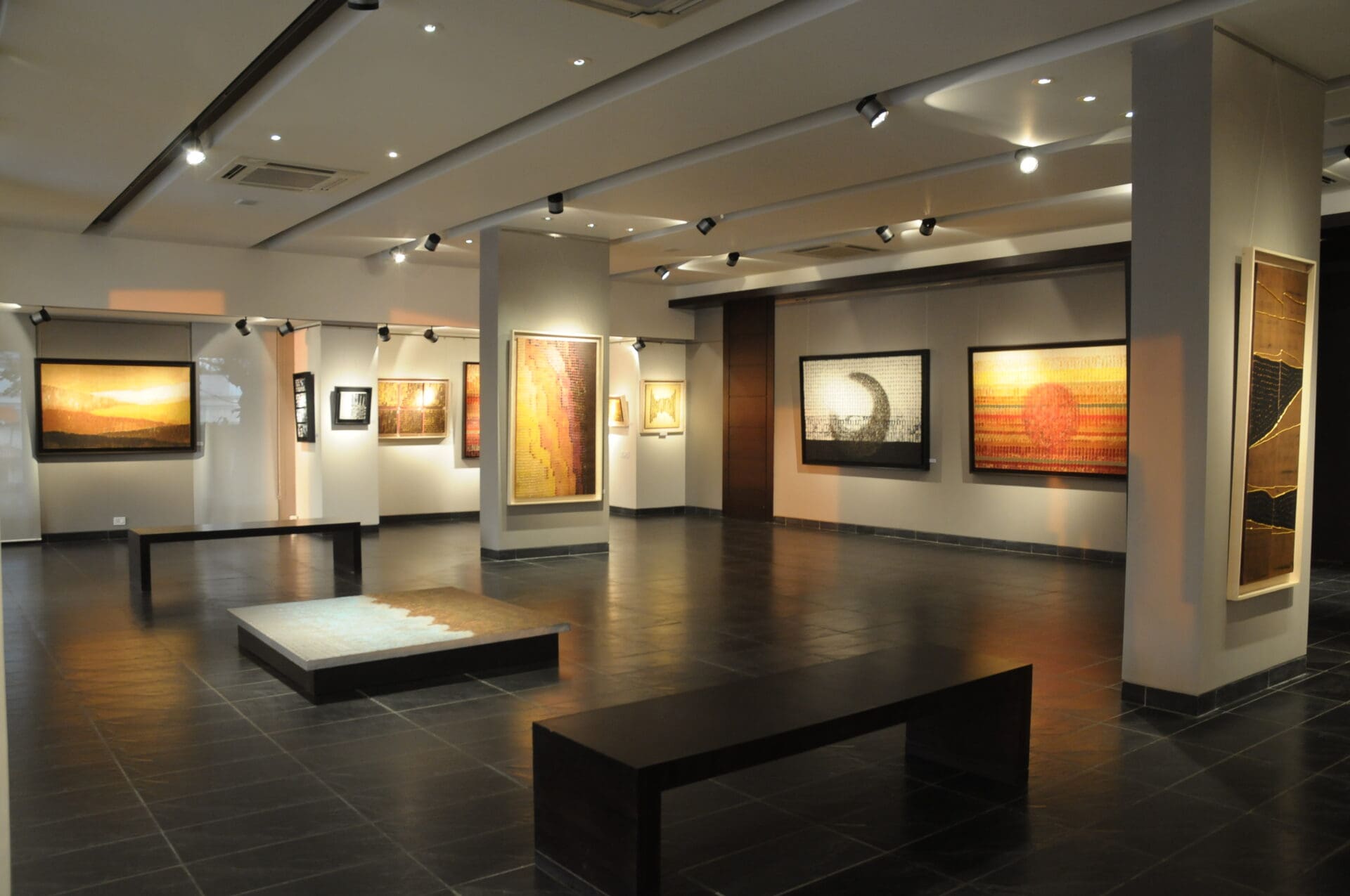 Best art galleries in Mumbai | A view of a gallery inside Tao Art Gallery, with works hung on the walls, and some benches in the centre of the room.