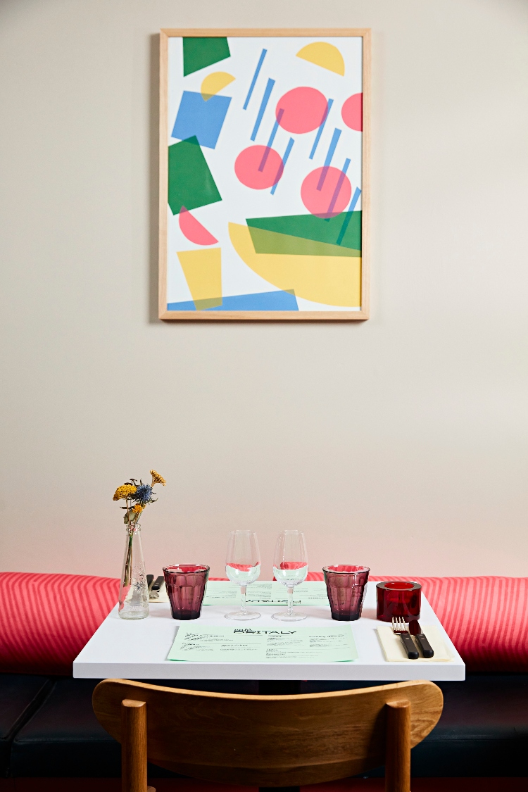 An abstract painting and pink seating frame a table at Café Britaly