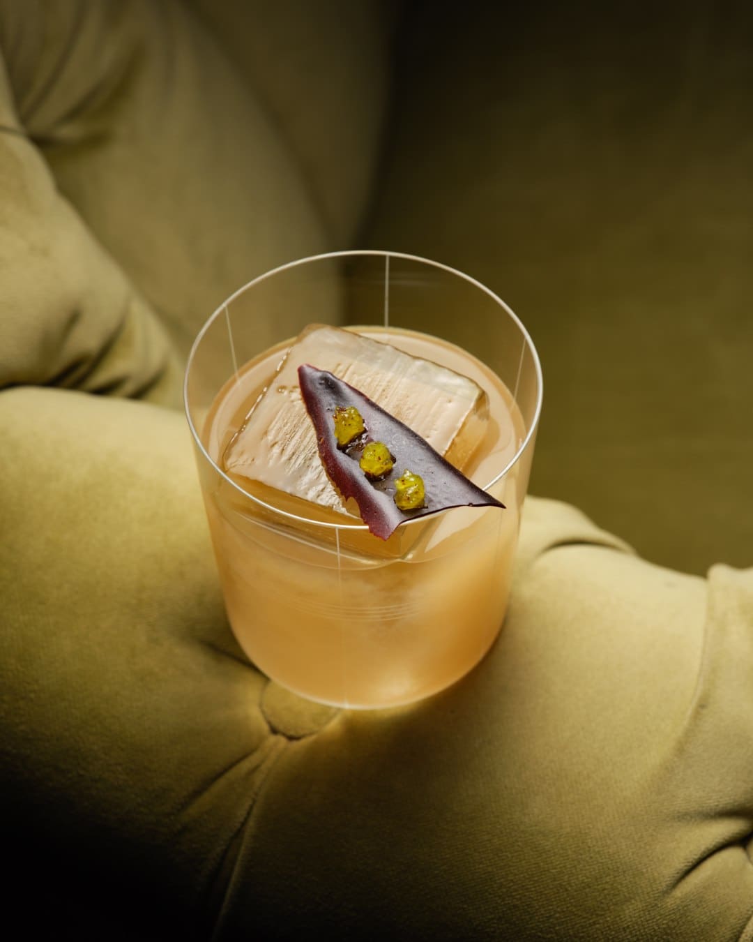 A glowing cocktail on a velvet chair arm at Rosewood London