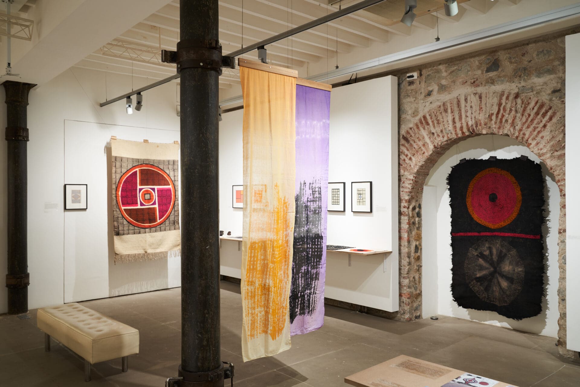 Best galleries in Mumbai | An installation view at Chatterjee & Lal in Mumbai, featuring hanging tapestries and a brick archway.