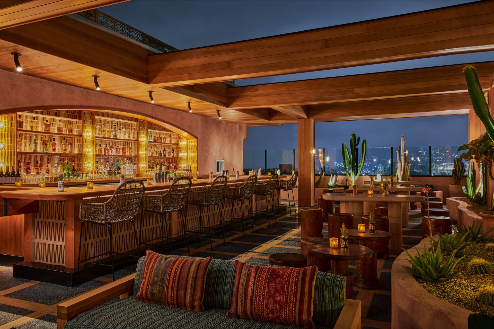 Best rooftop bars LA | The rooftop bar at Desert 5 Spot at night, with wooden tables under wooden beams silhouetted against a dark-blue sky