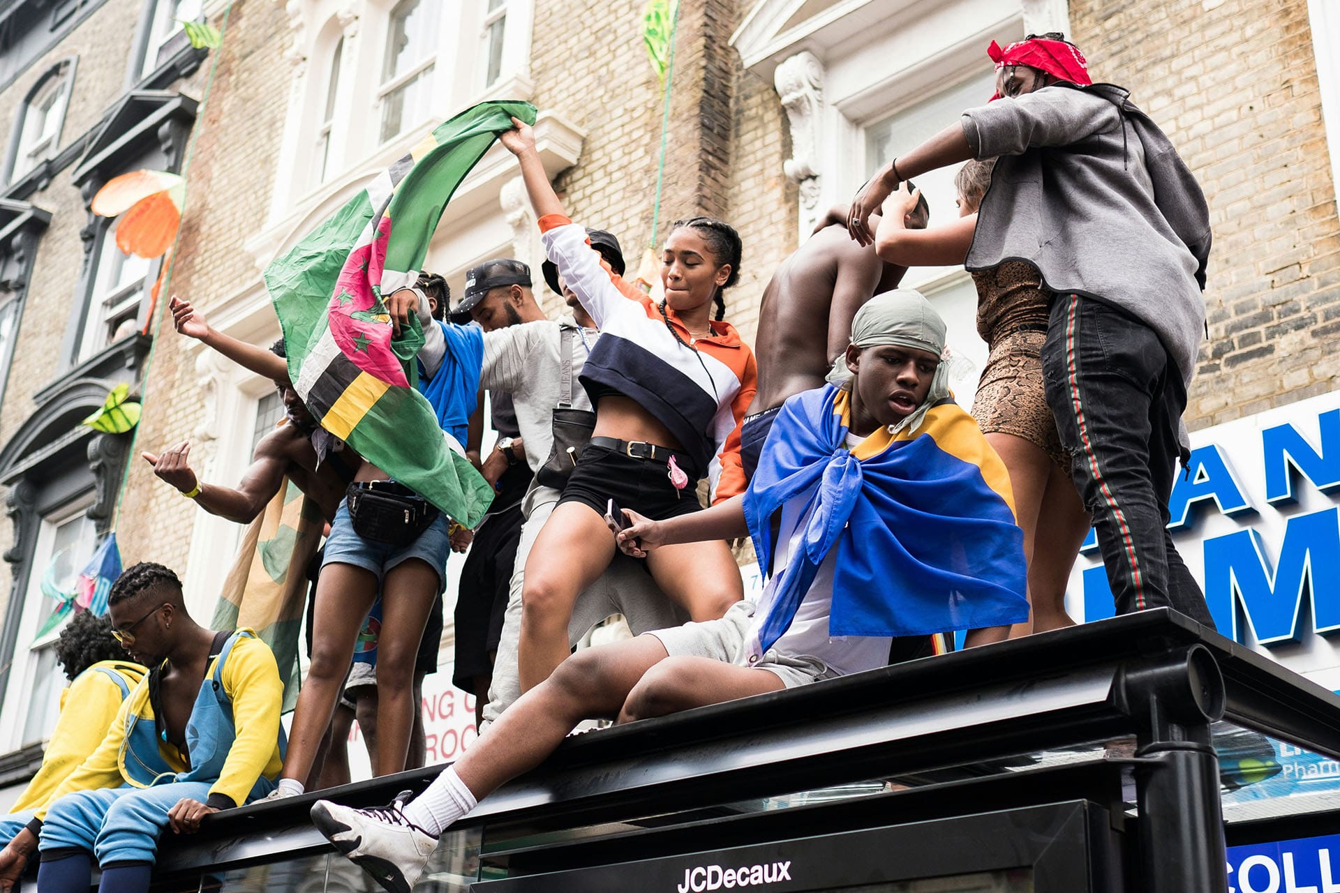 People dancing on top of a bus shelter at Notting Hill Carnival
