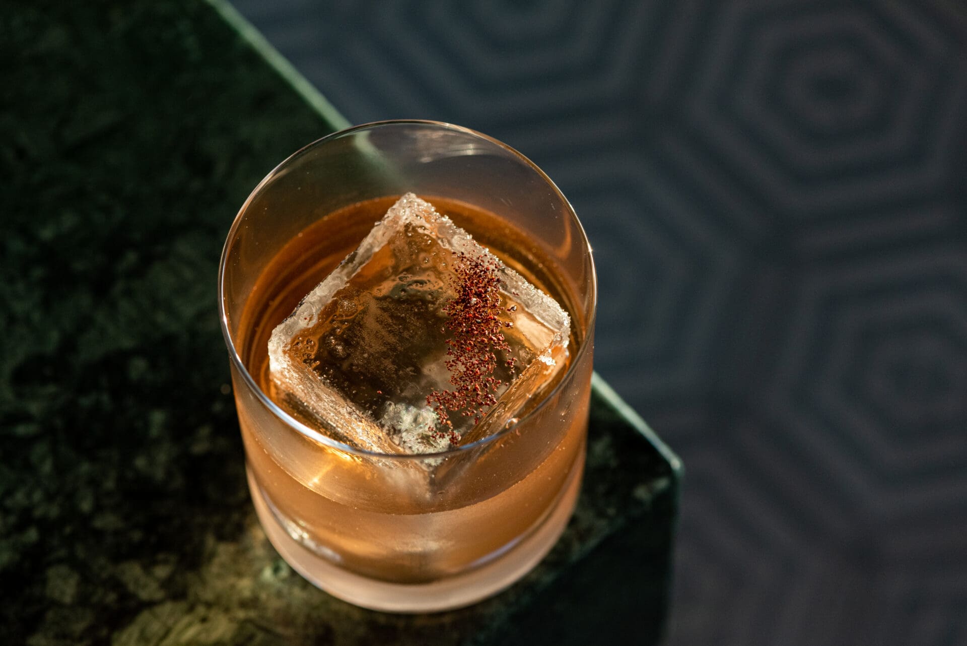 Best rooftop bars LA | a pinky-orange liquid with a large cube of ice sprinkled with spices in a short round cocktail glass at La Cha cha cha