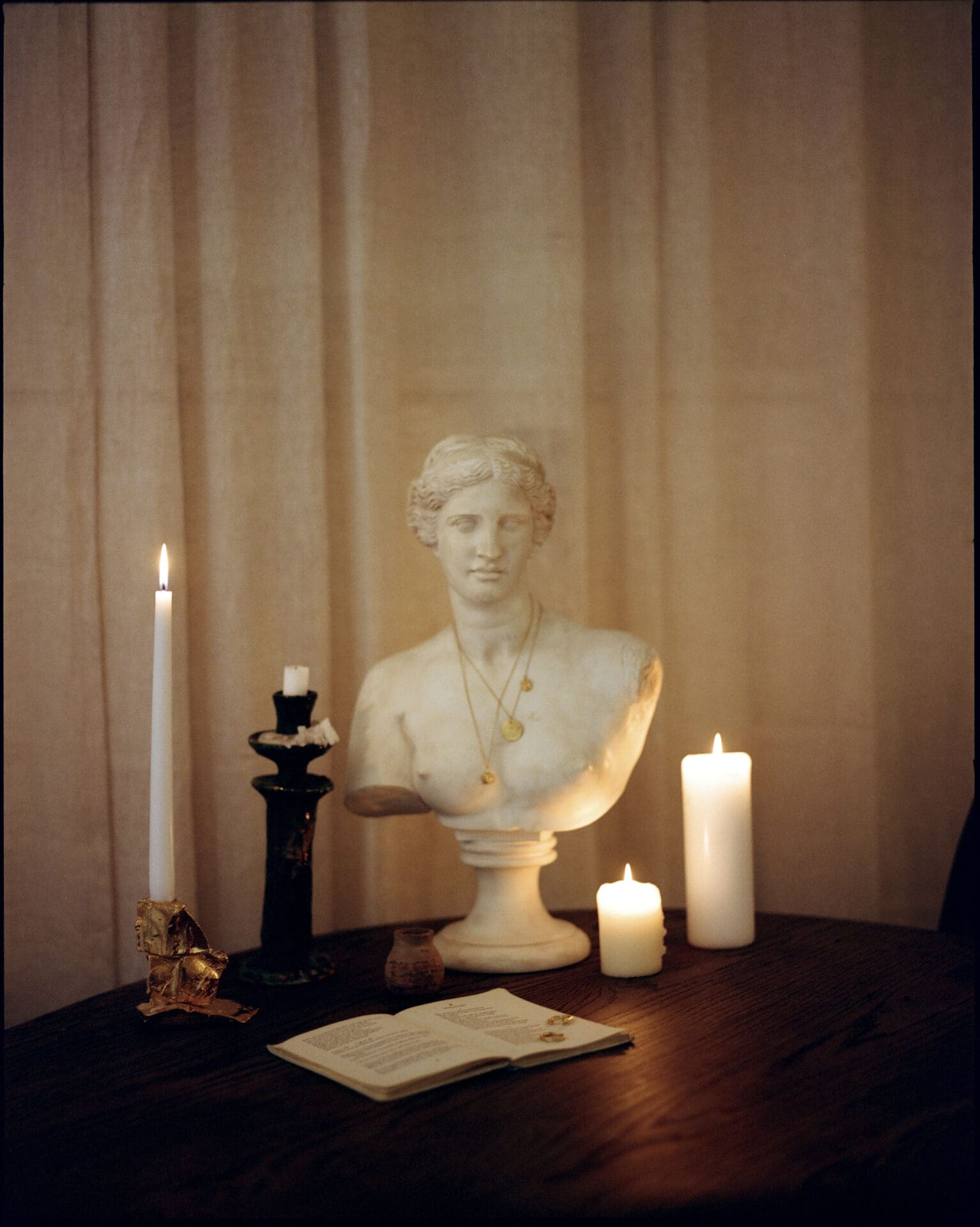 Rosh Mahtani, Alighieri | A Grecian bust wearing Alighieri imagery surrounded by candles