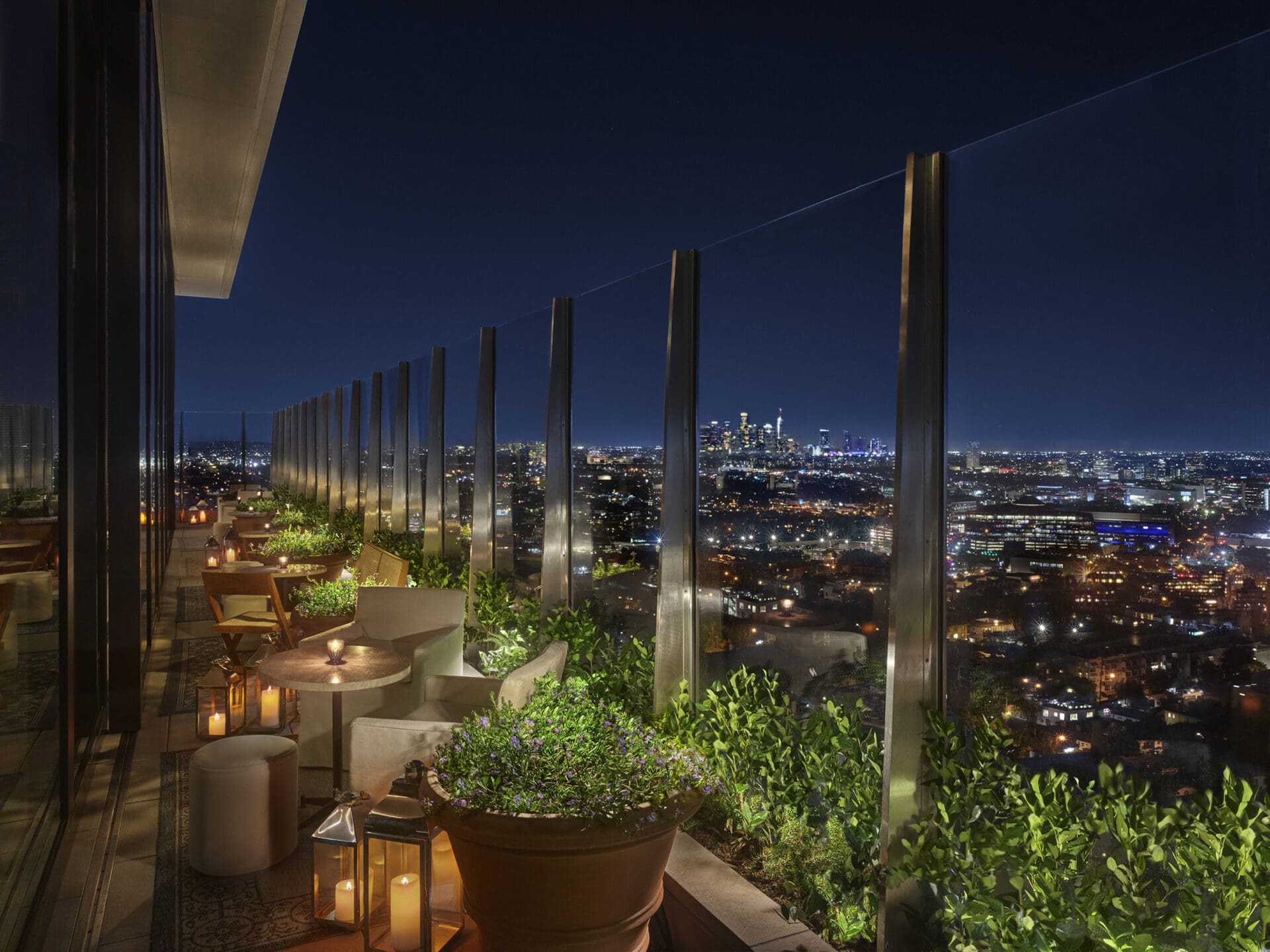 Upstairs bar at the West Hollywood EDITION at night, with intimate table topped with glowing tea lights, and views over LA