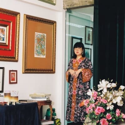 Phannapast | The Bangkok artist wearing a floral kimono in her studio, with white walls and colourful artwork in frames