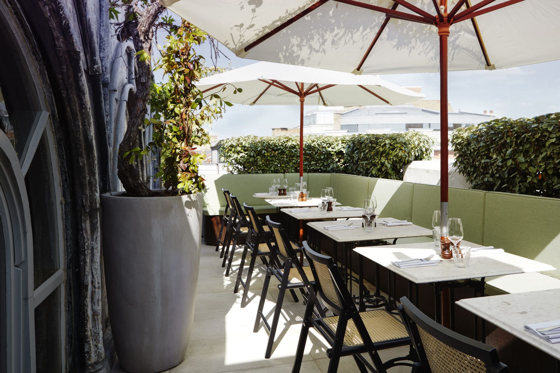 Best outdoor restaurants London | The rooftop at Sessions Arts Club, with a row of tables and chairs under white umbrellas and with light-green cushions