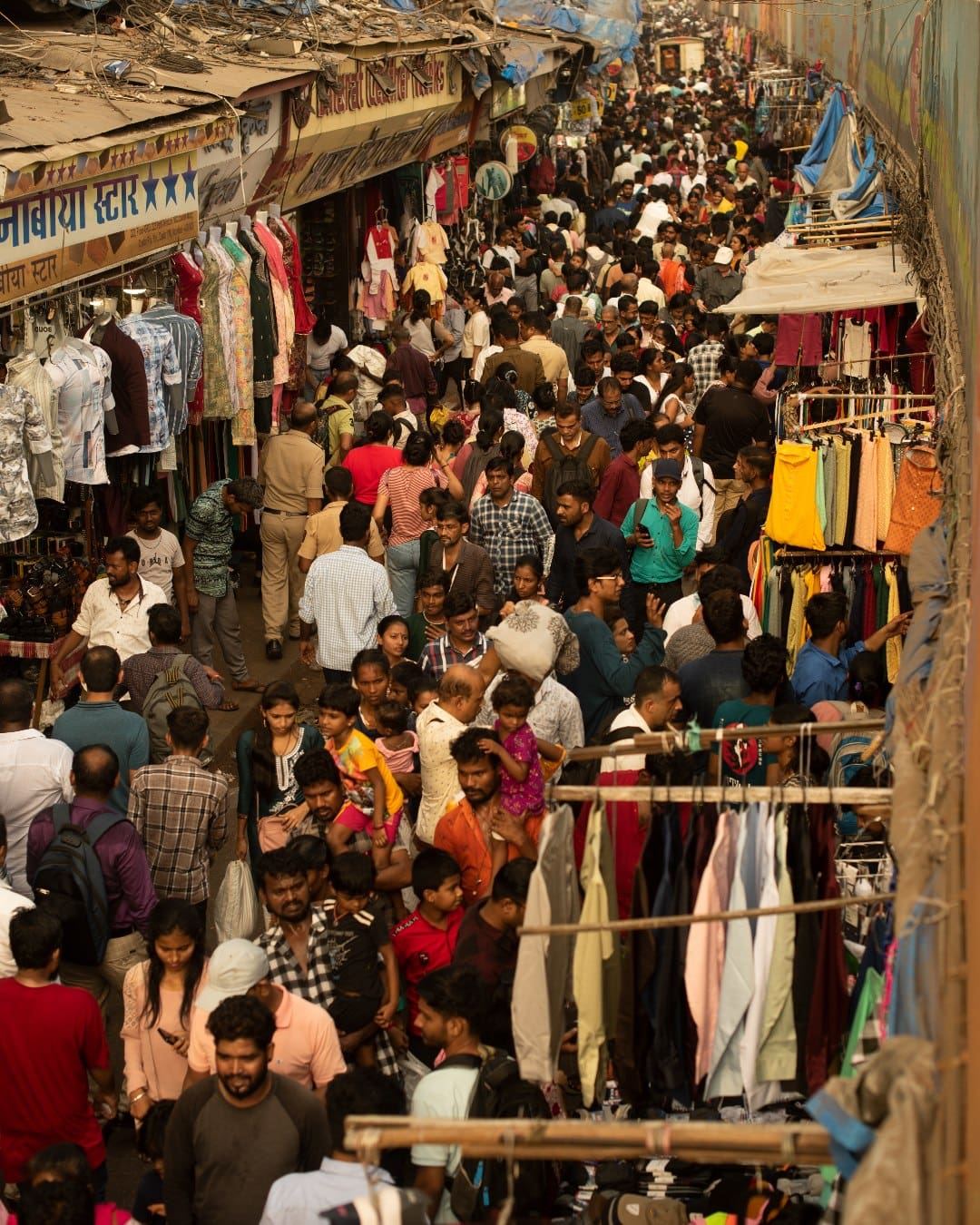 A busy street market scene in Mumbai, with throngs of people