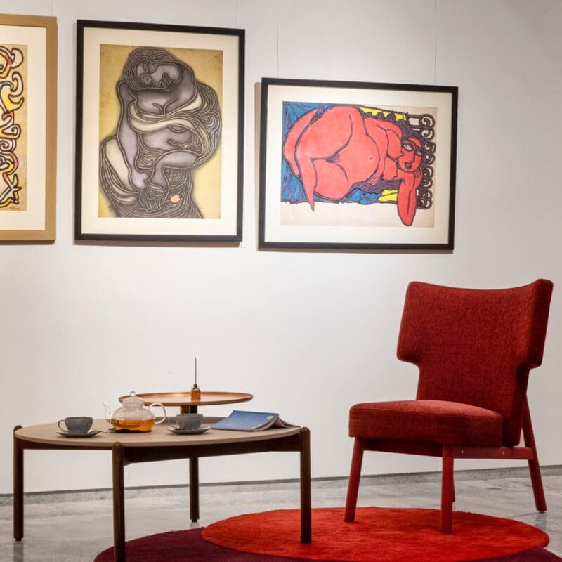 Best co-working spaces in Mumbai | A circular red carpet and a red armchair in front of a white wall adorned with artwork at Kathiwada City House