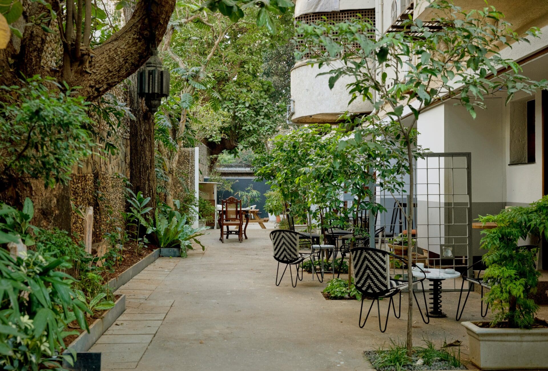 Best co-working spaces in Mumbai | The outdoor area at Kathiwada City House, with a paved patio, a tree a wrought-metal furniture