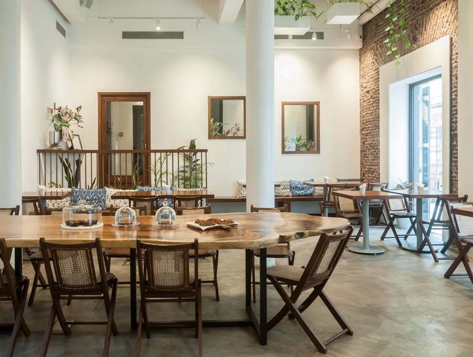 Best co-working spaces Mumbai | A large round wooden table with wooden chairs in a room with white walls and a concrete floor