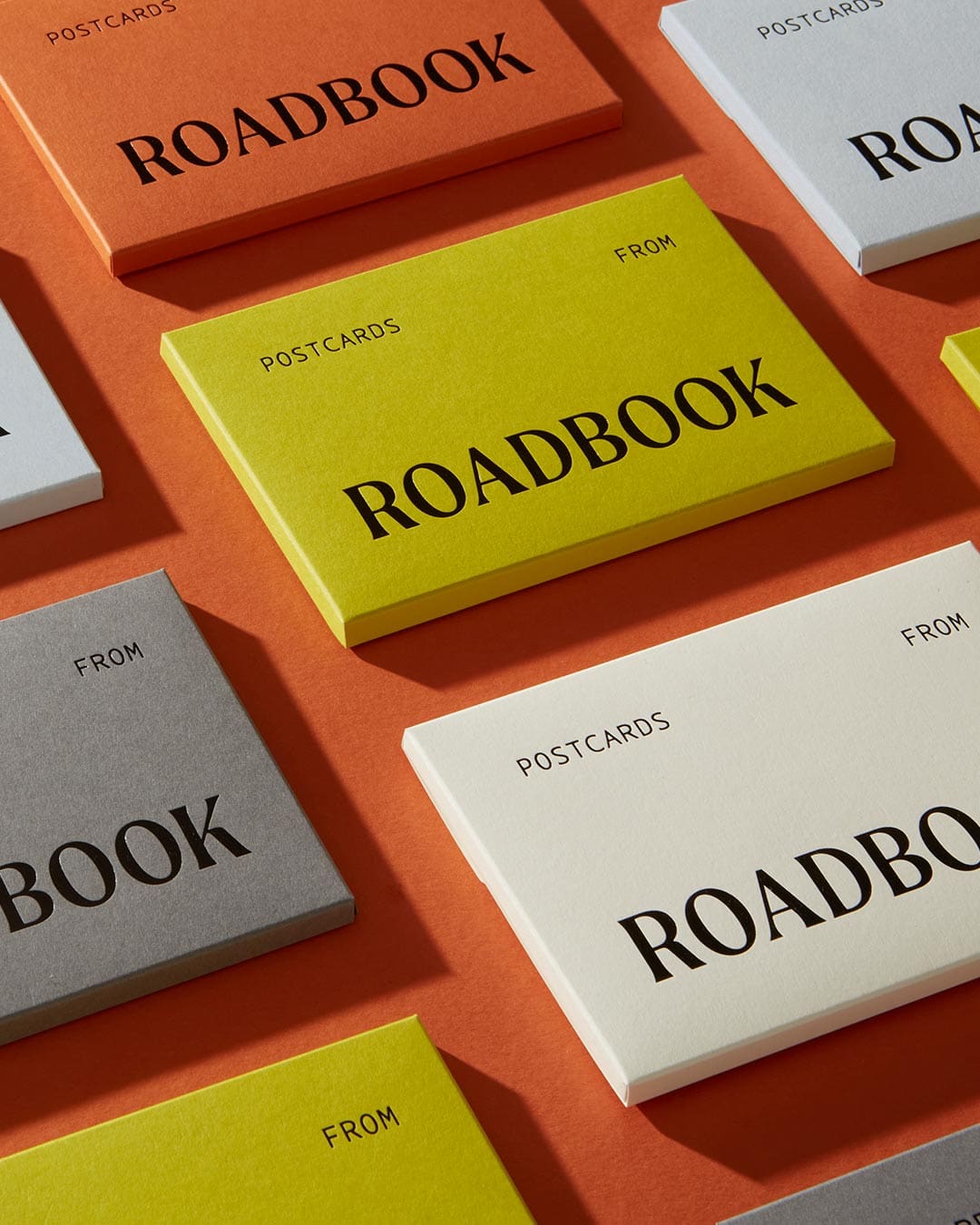 Postcards from ROADBOOK | Brightly coloured boxes in orange, green, white and grey emblazoned with the words ROADBOOK sit against an orange background