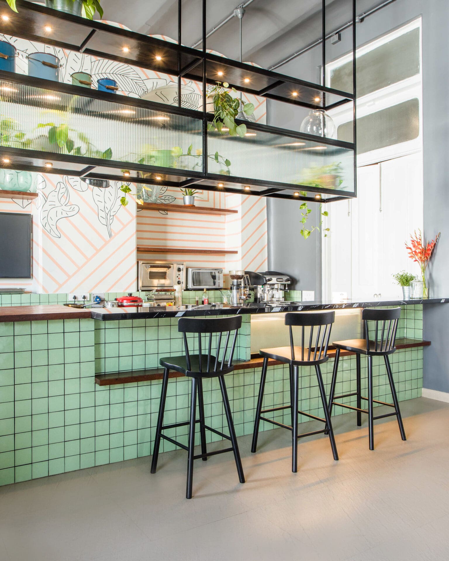 Best co-working spaces Mumbai | the counter area at The Ministry of New Café Savor, with mint green tiles and dark-wood stools in front of a white-tiled back bar