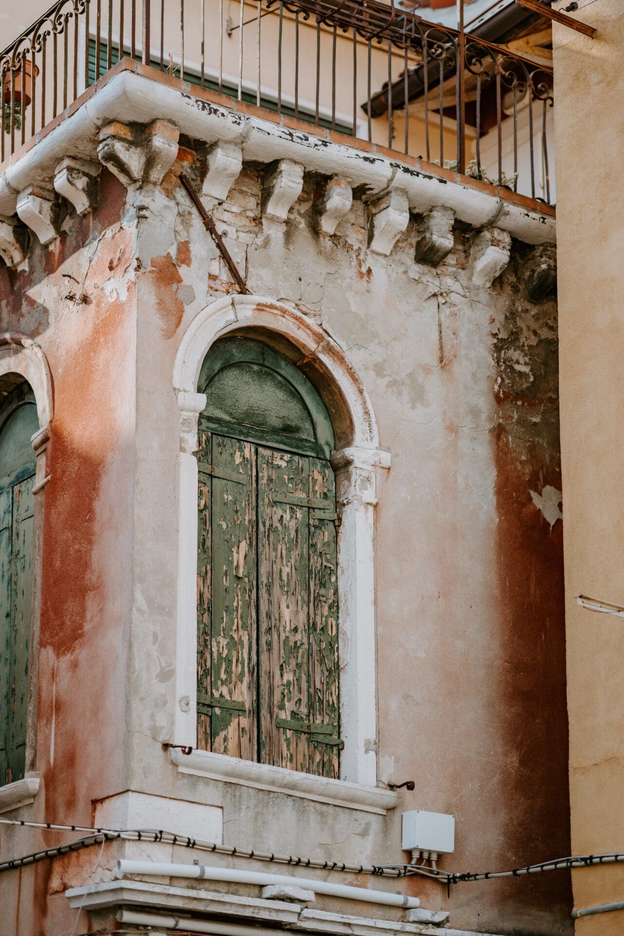Running in Venice | One of Venice's dilapidated buildings, with bare, pink-hued walls, ornate stucco and delicate ironwork