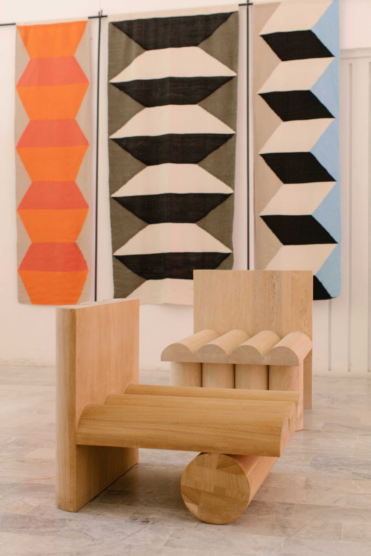 Javier Reyes, rrres studio, Oaxacao | A light-wooden chair in front of a graphic painting with trompe l'oeil shapes
