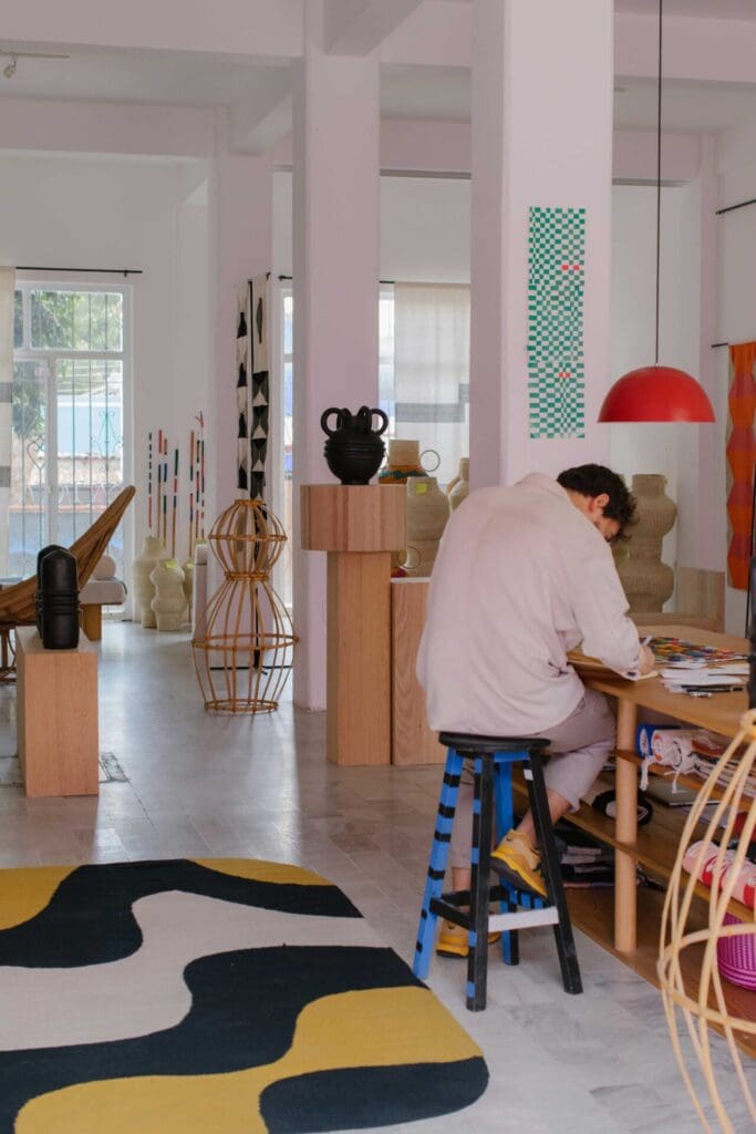 Javier Reyes, rrres studio, Oaxaca | the design hunches over his desk while he works in his colourful yet minimalist studio