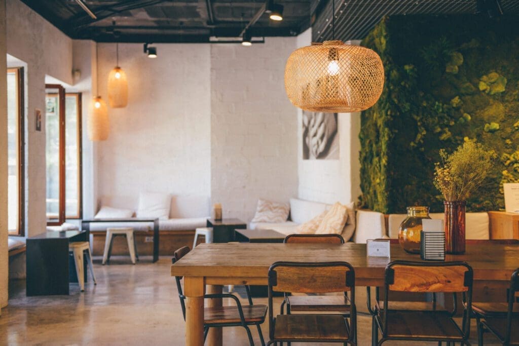 The best European cities for remote working | An interior view of Simple Cafe in Palma, Mallorca, with a wooden table and chairs, a hanging rattan lampshade and plenty of greenery