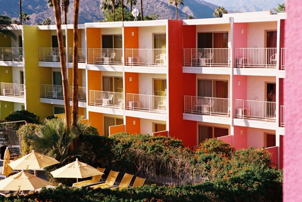 What to do in Palm Springs, California | A block of rooms at Saguaro Hotel, their walls painted in yellow, orange, red and pink