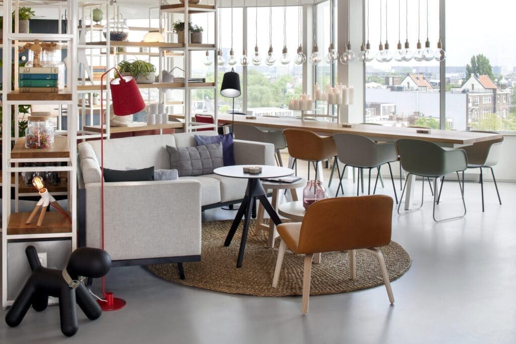 The best European cities for remote working | Inside the bright co-working space at Zoku in Amsterdam, with a woven rug on a concrete floor and low, wide chairs in shades of green and orange