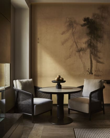 The best new hotels around the world | The pared-back interiors of the Aman in NEw York, with pale-yellow walls and to dark-wood chairs with white cushions at a round table topped by a fruit bowl