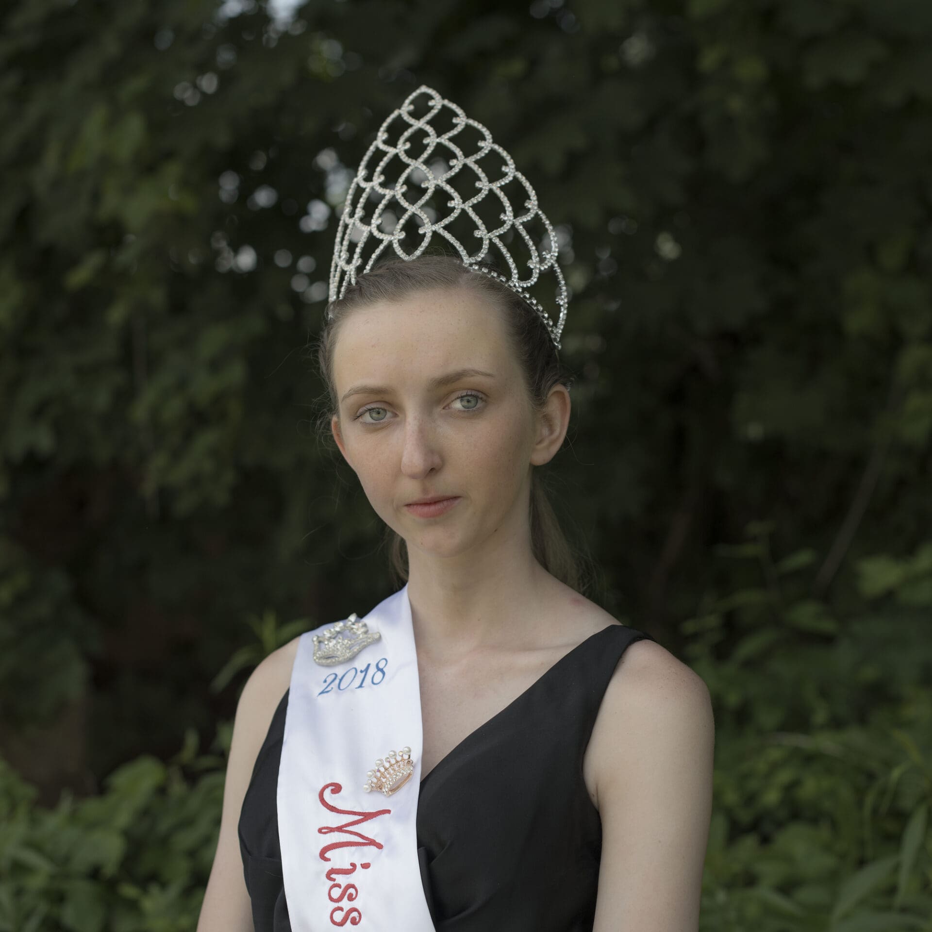 Photographer Rich-Joseph Facun | A young girl with brown hair and wearing a black dress wears a high tiara and a sash