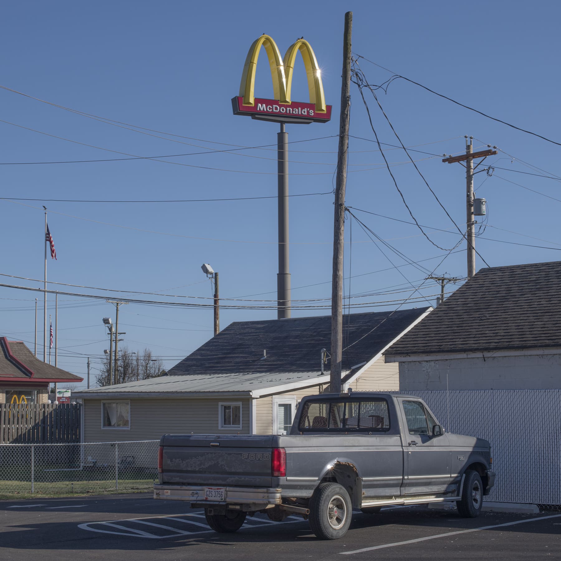 Photographer Rich-Joseph Facun | a grey pickup truck is park against the back of a white-boarded house underneath a McDonalds sign