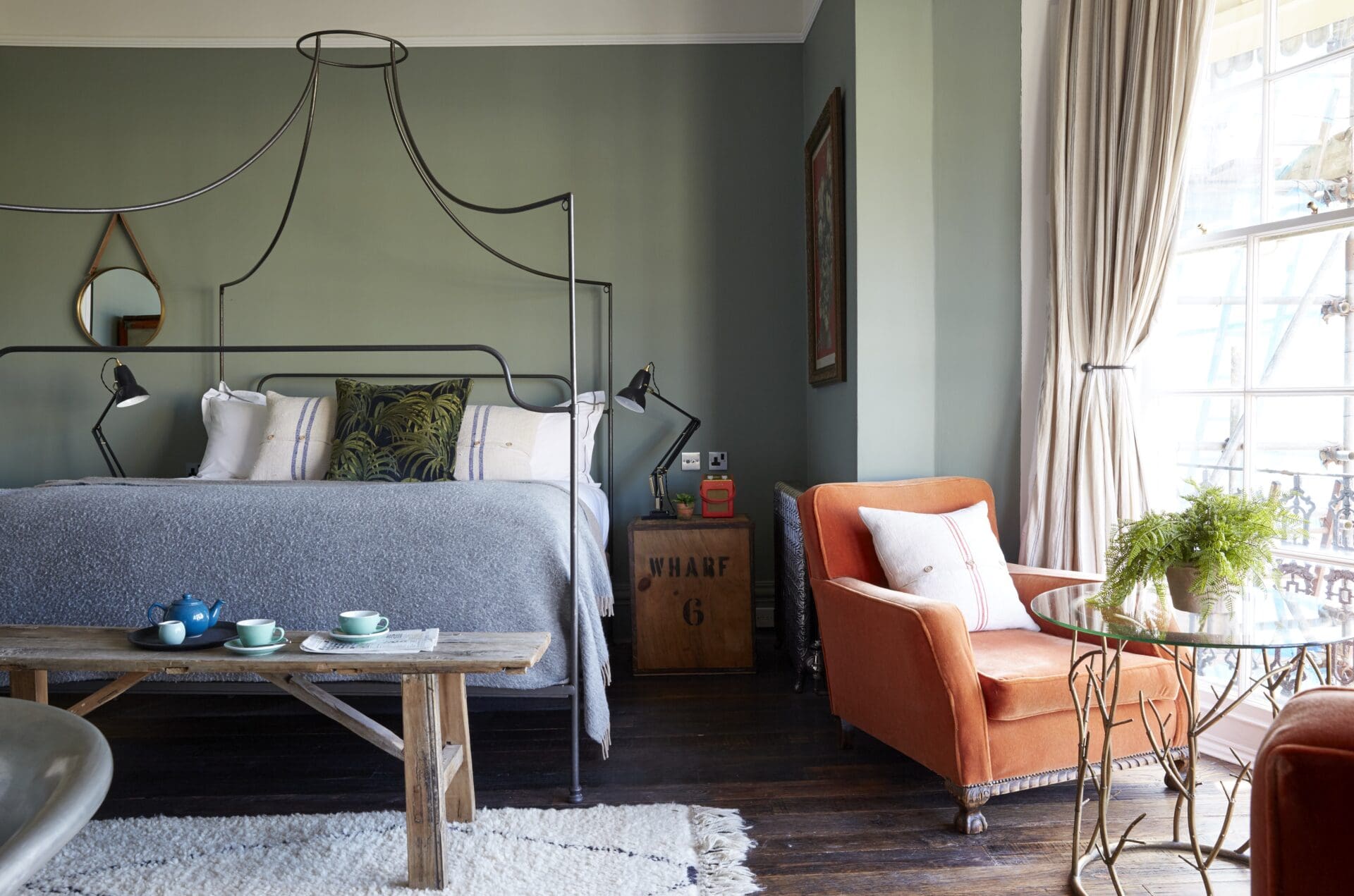 A bedroom at the Artist Residence hotel in Brighton, with a double bed and velvet seat by a bay window.