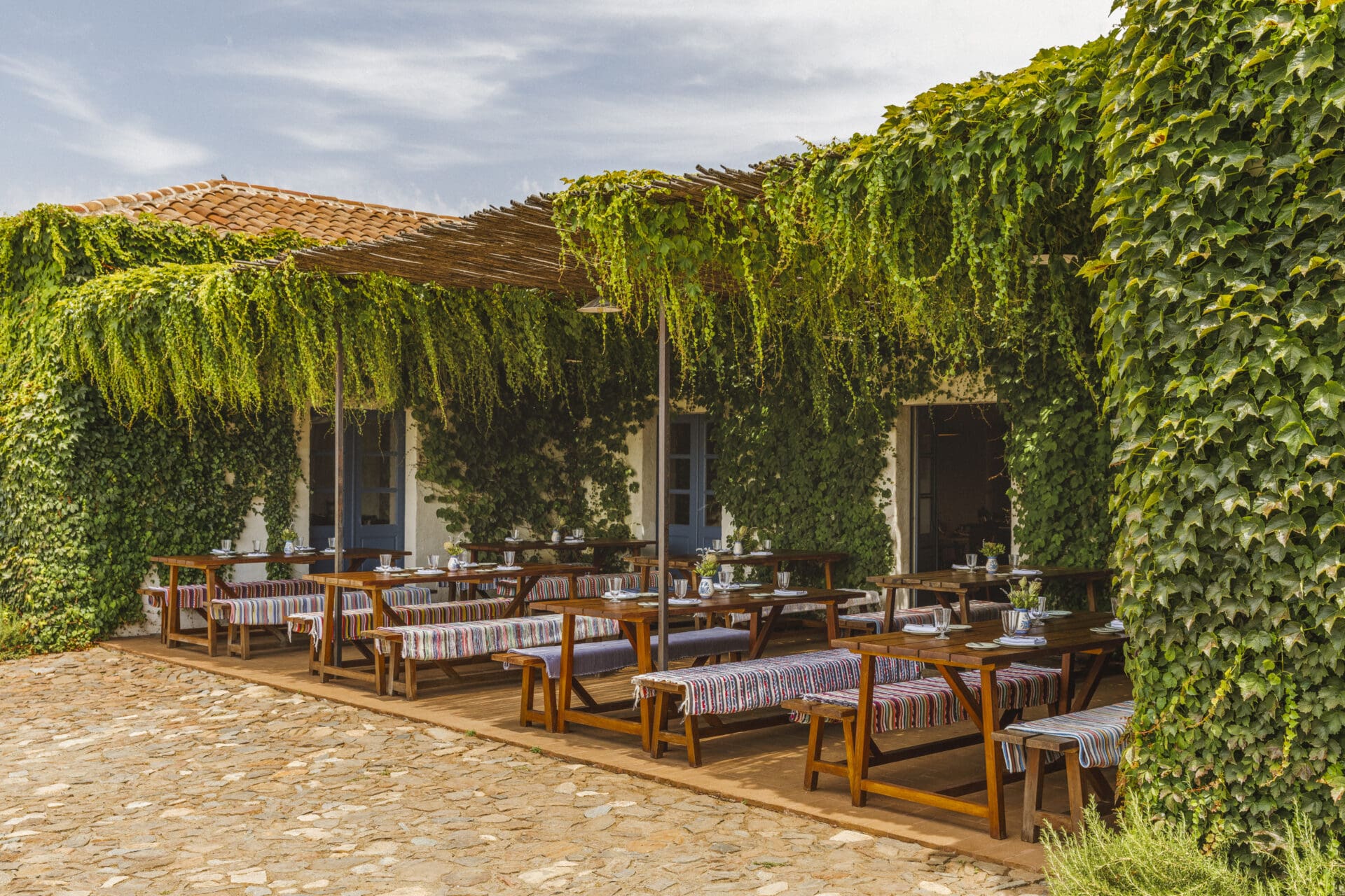 São Lourenço do Barrocal | Wooden benches with blue and white blankets sit on a patio festooned with greenery