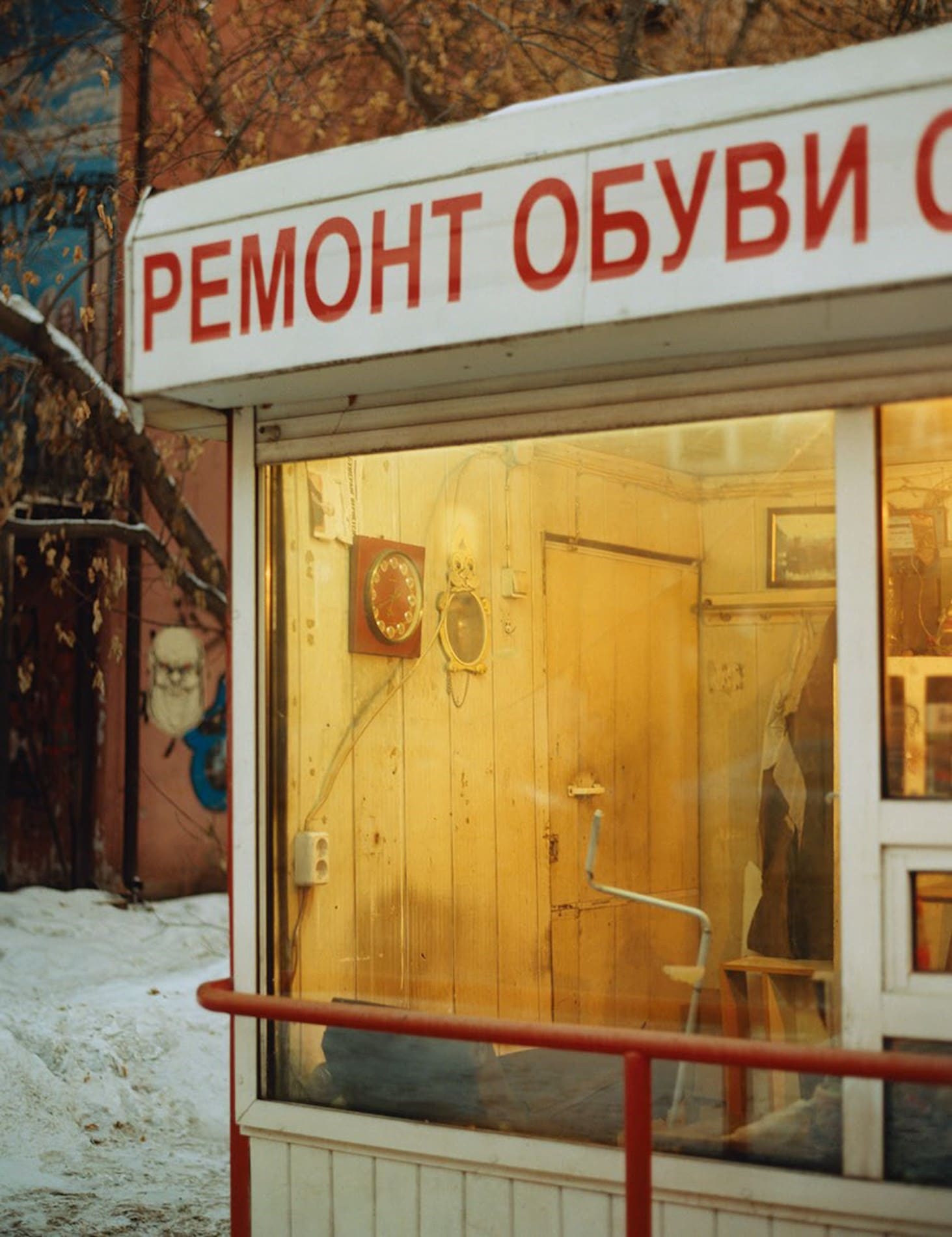 Coco Capitan | A view through a front window illuminated by yellow light into a shop or restaurant, with Cyrillic lettering above